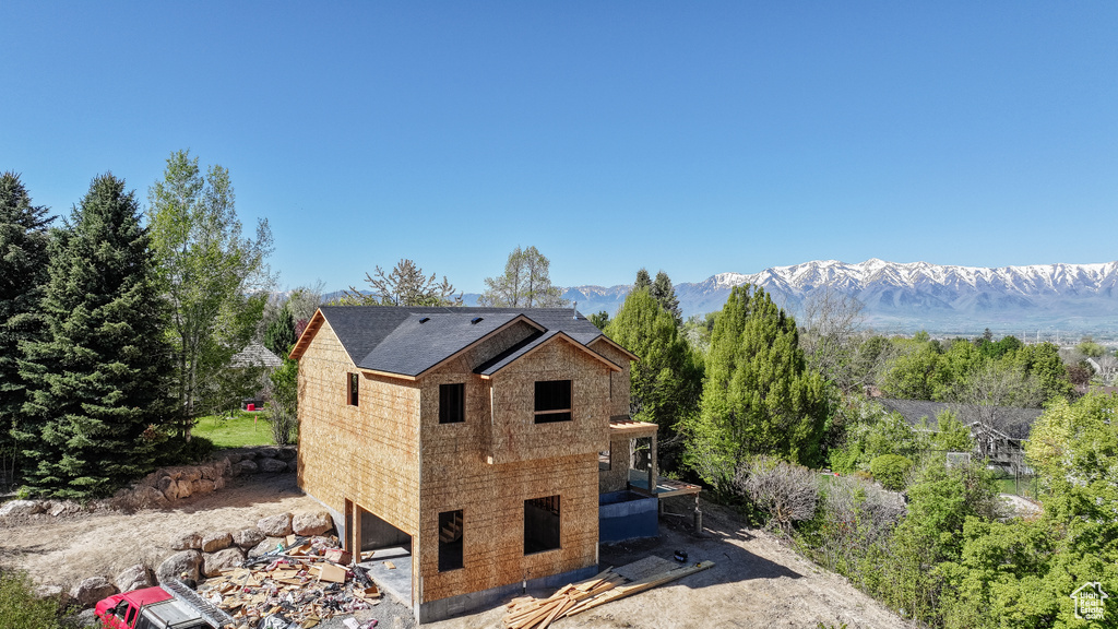 Back of house with roof with shingles and a mountain view
