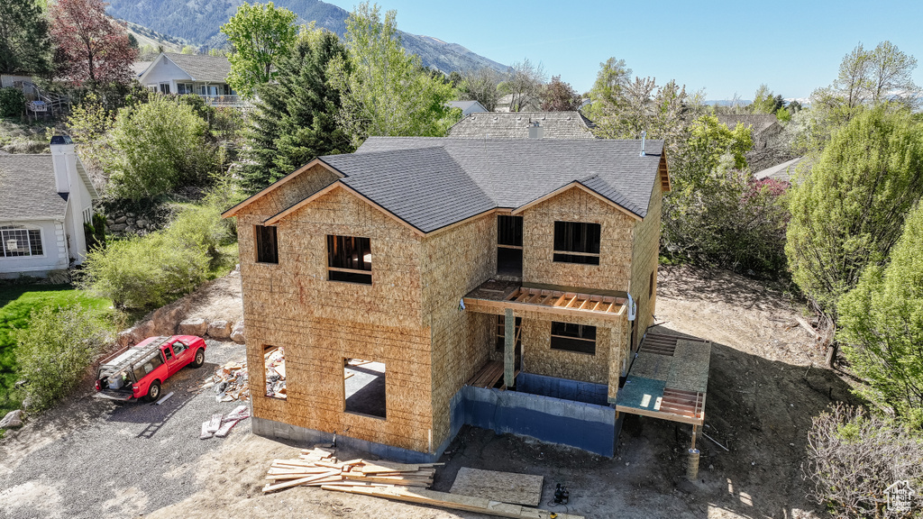 Exterior space featuring stone siding, a mountain view, and roof with shingles