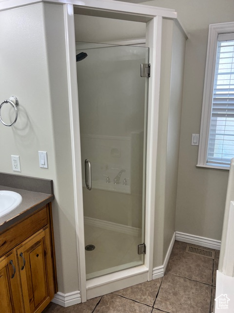 Bathroom featuring a stall shower, tile patterned flooring, vanity, and baseboards