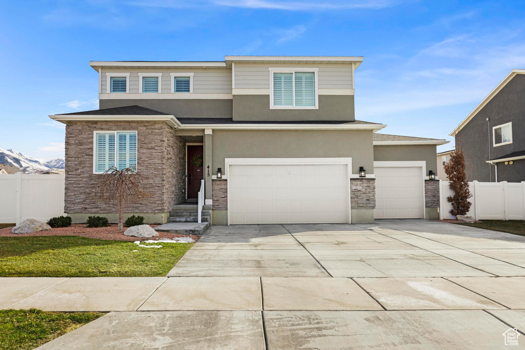 Prairie-style house featuring fence, stone siding, driveway, and stucco siding