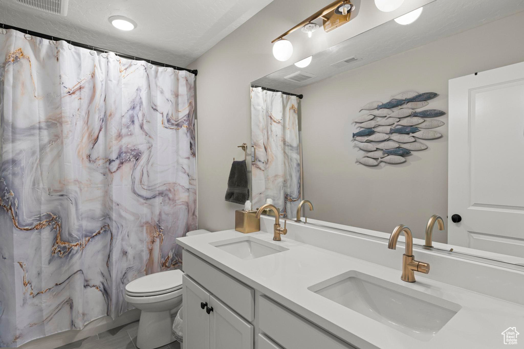 Bathroom featuring a sink, visible vents, toilet, and double vanity
