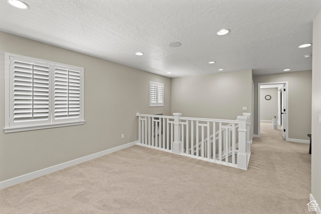 Carpeted spare room featuring recessed lighting, a textured ceiling, and baseboards