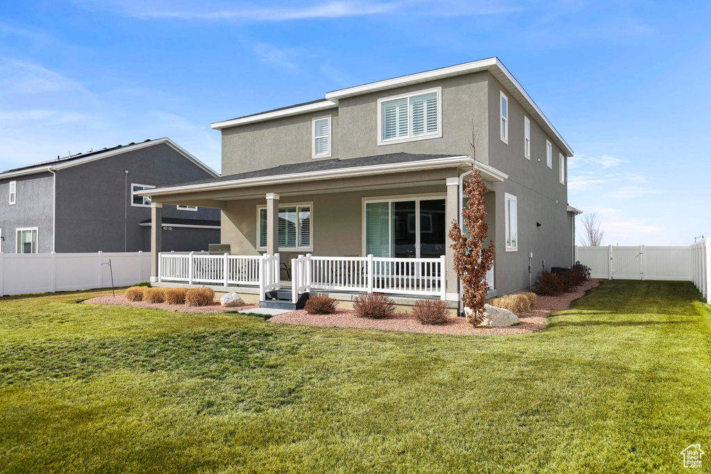 View of front of property featuring covered porch, fence, a front lawn, and stucco siding