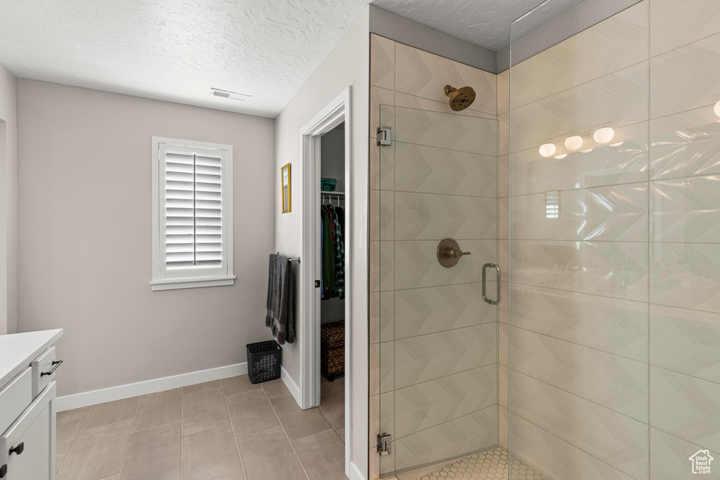 Full bathroom with vanity, visible vents, baseboards, a shower stall, and a textured ceiling