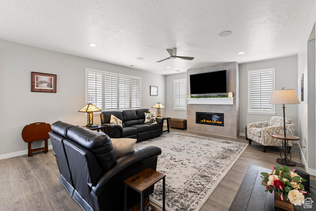 Living room featuring a ceiling fan, wood finished floors, and a healthy amount of sunlight