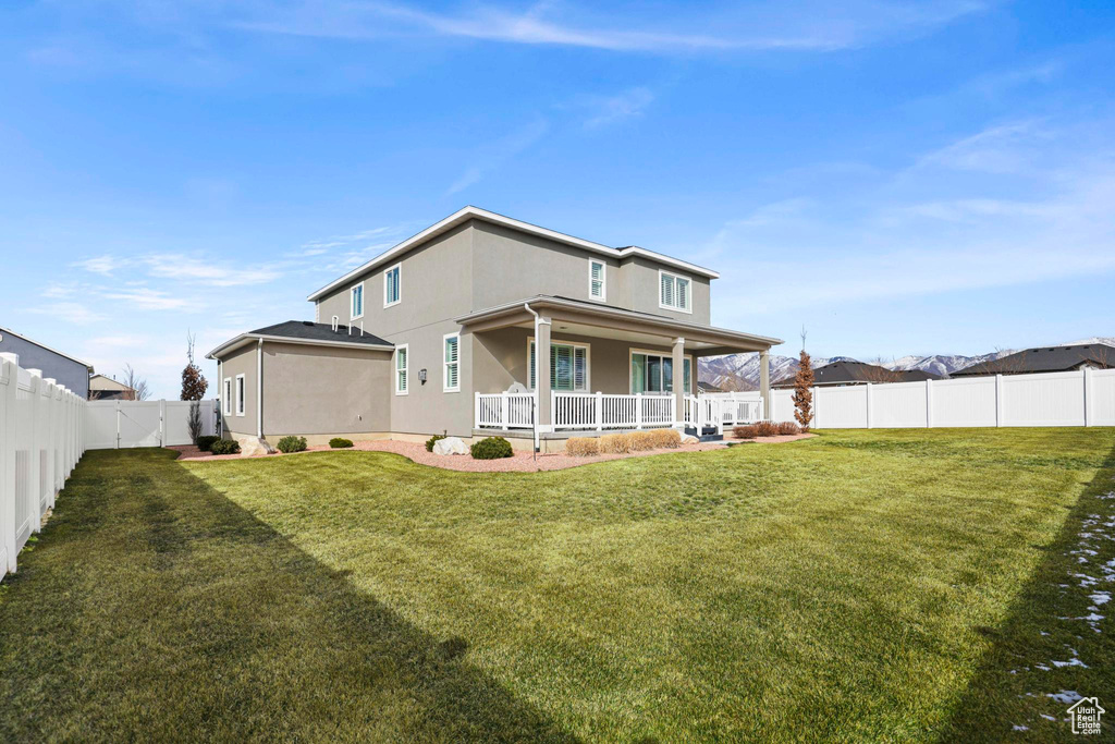 Rear view of property featuring a yard, a porch, a fenced backyard, and stucco siding