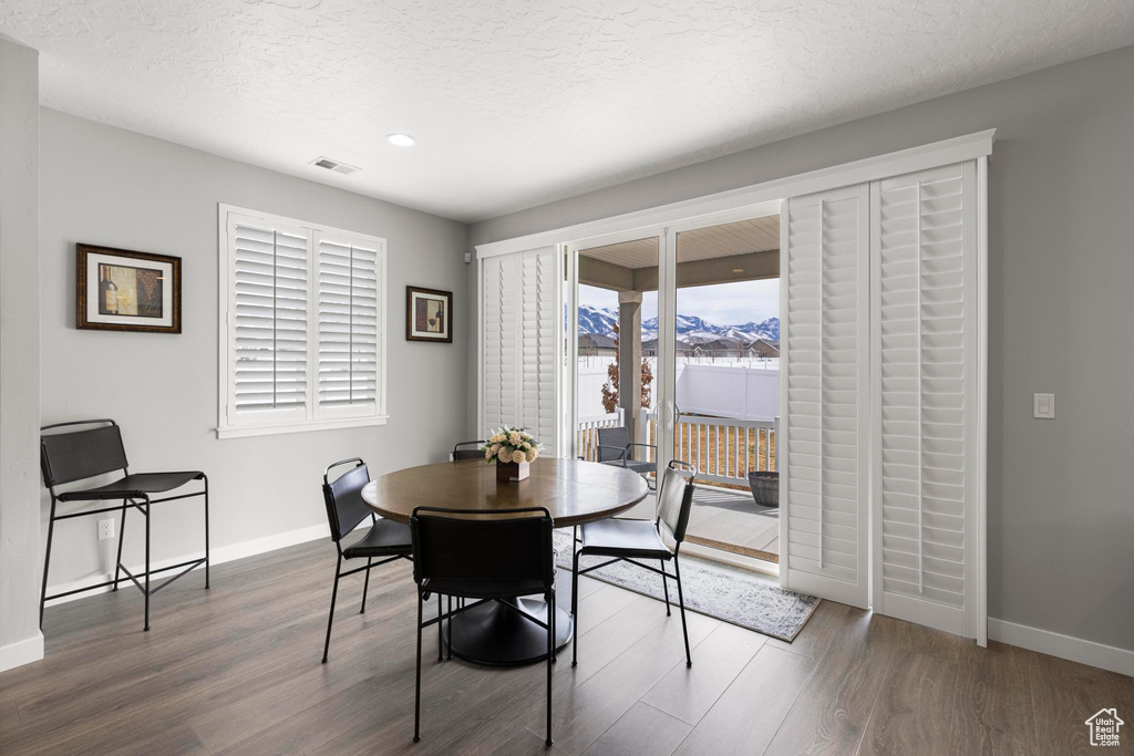 Dining area featuring a textured ceiling, wood finished floors, visible vents, and baseboards