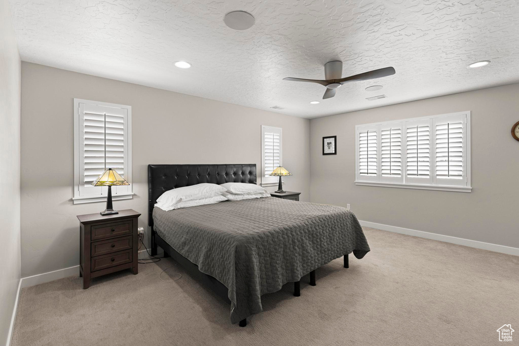 Carpeted bedroom with ceiling fan, recessed lighting, baseboards, and a textured ceiling