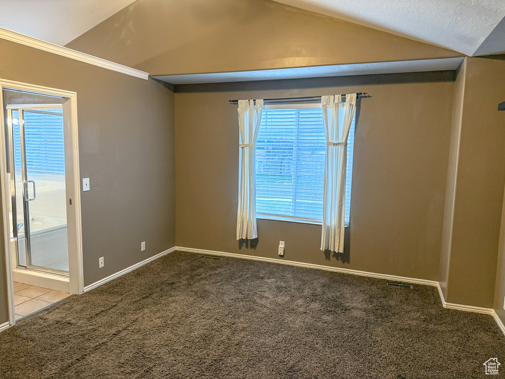 Tiled empty room with carpet flooring, baseboards, and lofted ceiling