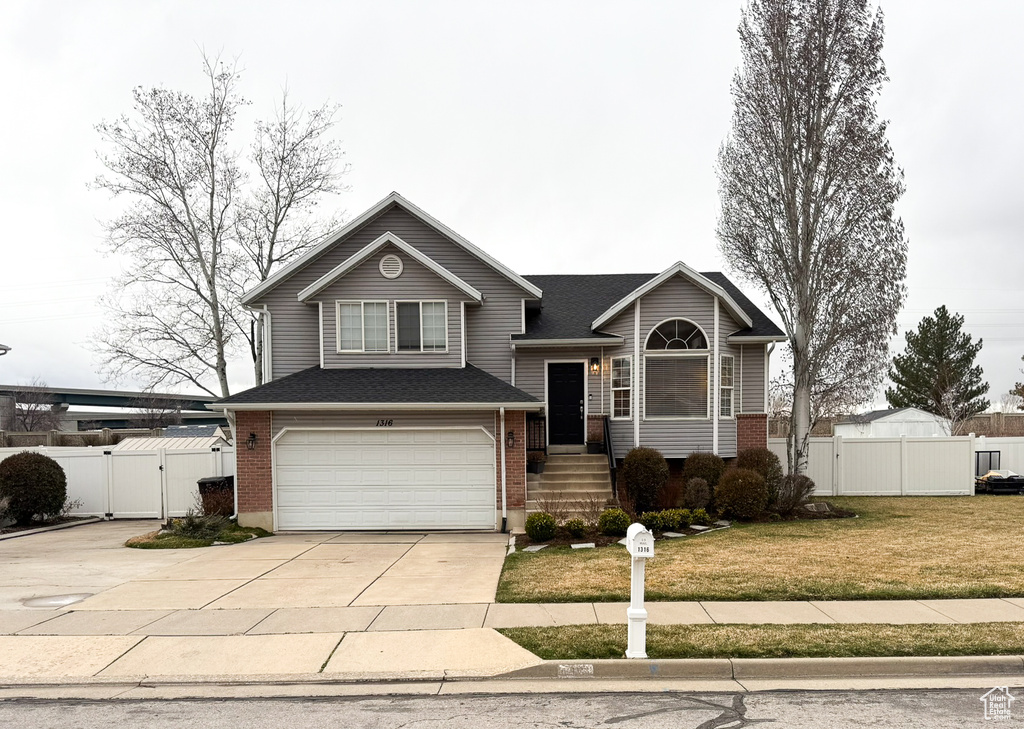 View of front of house with a gate, fence, concrete driveway, a garage, and brick siding