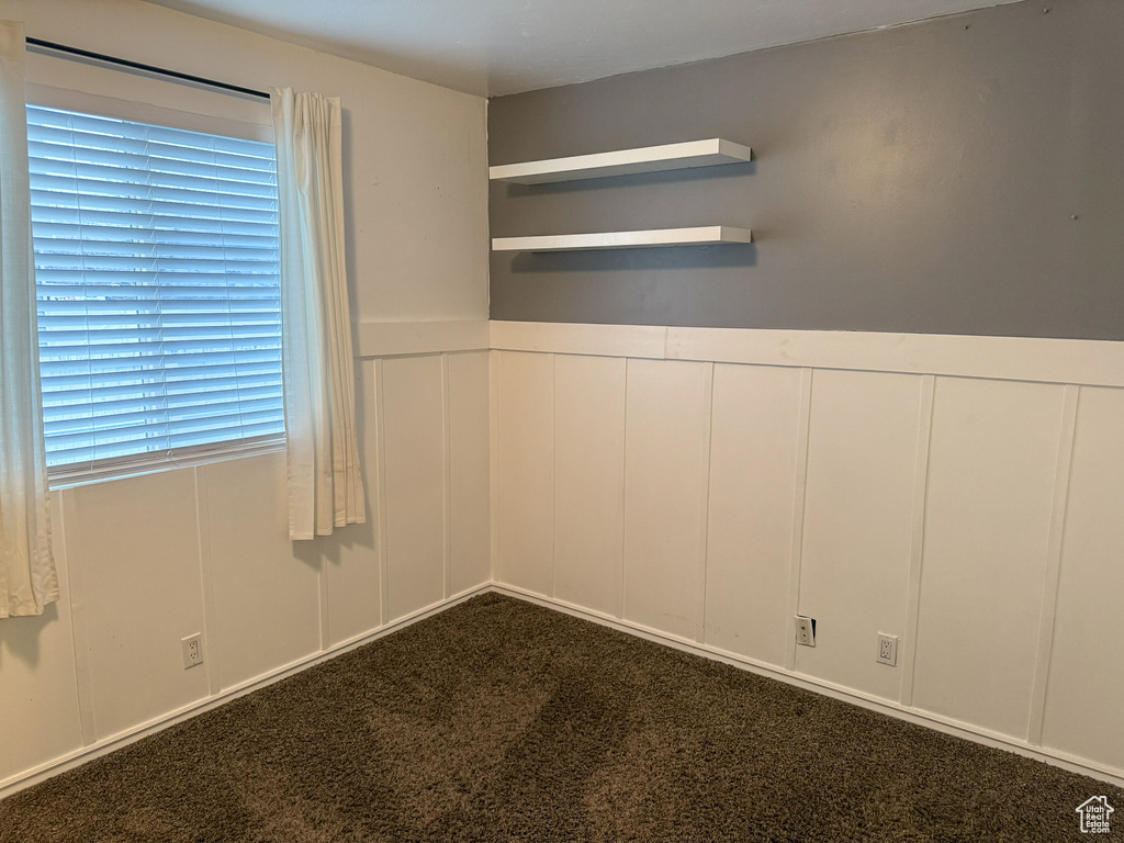 Unfurnished room with a decorative wall and dark carpet