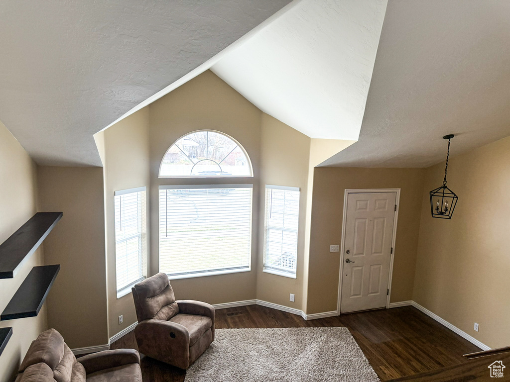 Interior space with vaulted ceiling, a textured ceiling, baseboards, and wood finished floors