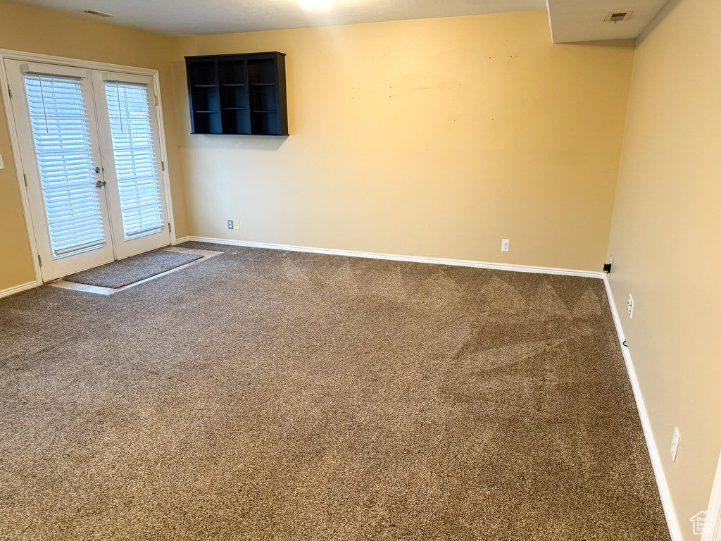 Carpeted empty room with visible vents, french doors, and baseboards
