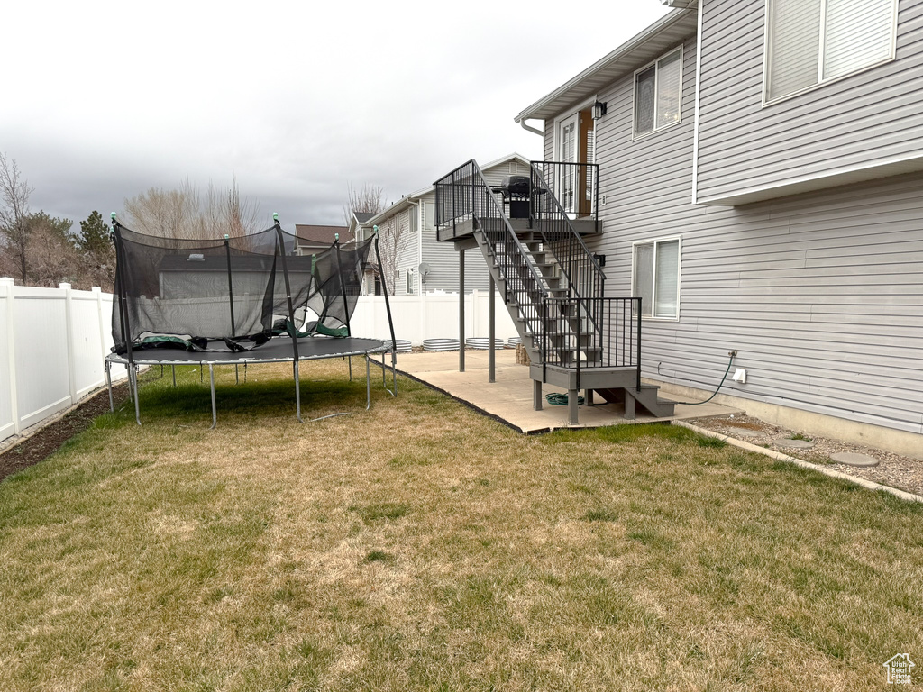 View of yard with stairs, a patio area, a trampoline, and fence