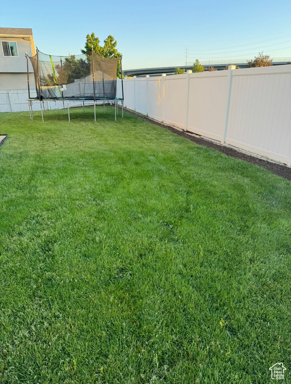 View of yard featuring a trampoline and a fenced backyard