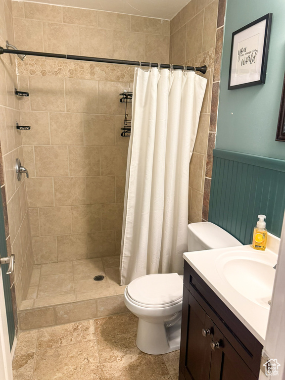 Full bath with stone finish flooring, vanity, toilet, and a shower stall