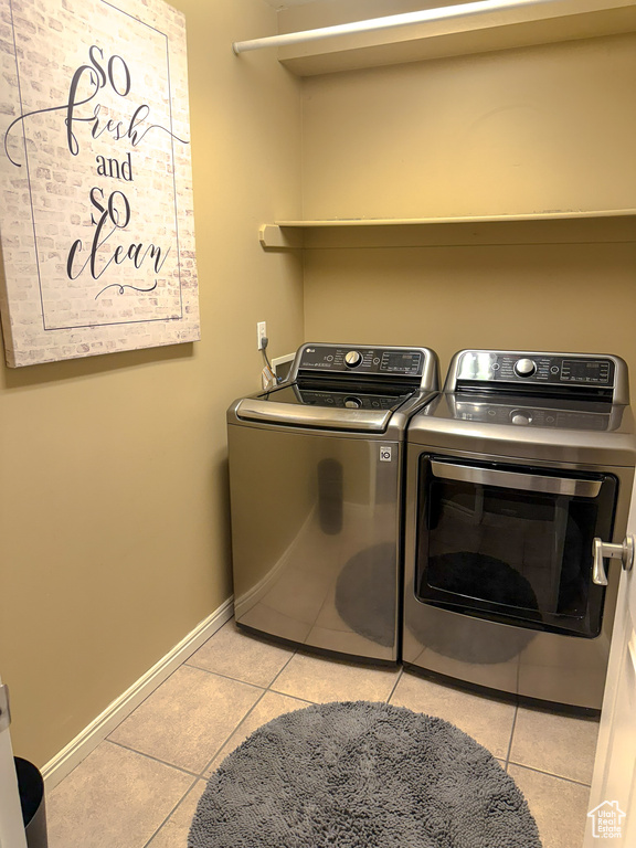 Washroom with laundry area, light tile patterned flooring, baseboards, and independent washer and dryer