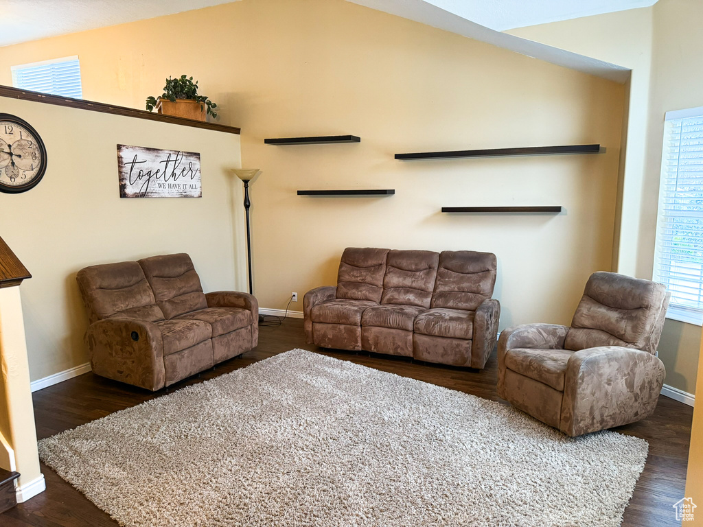 Living room featuring dark wood-style floors, baseboards, and vaulted ceiling