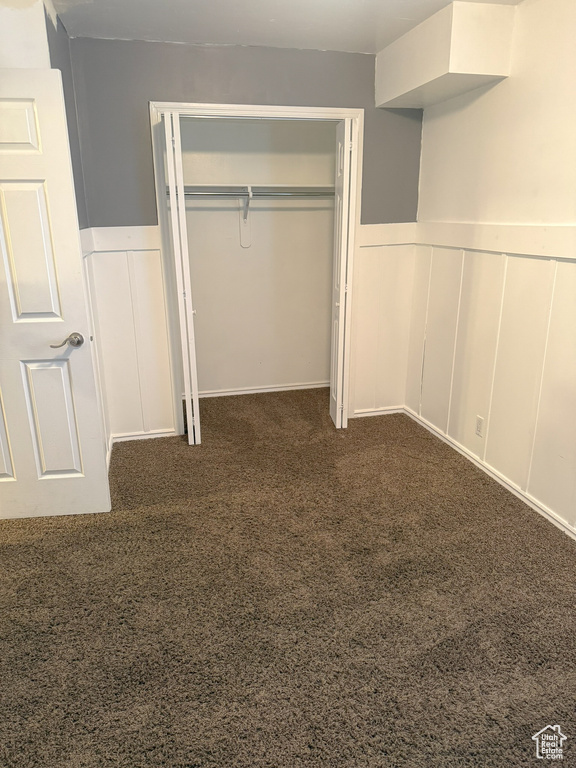 Unfurnished bedroom with a closet, carpet floors, wainscoting, and a decorative wall