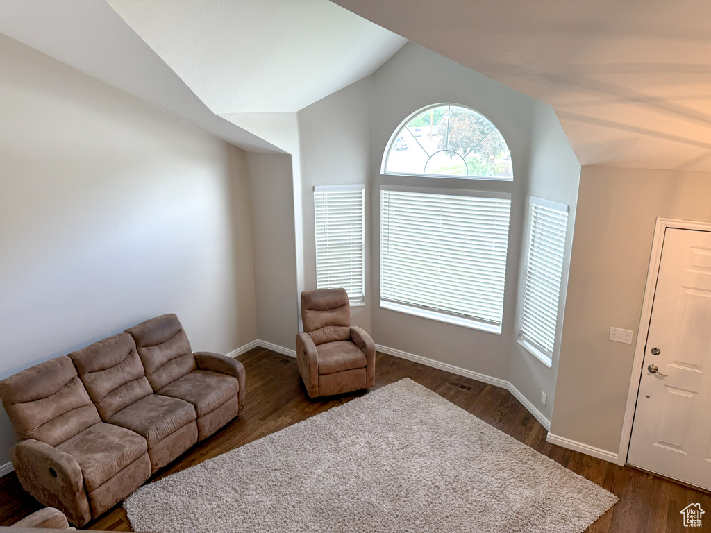 Living room featuring vaulted ceiling, dark wood-style floors, and baseboards