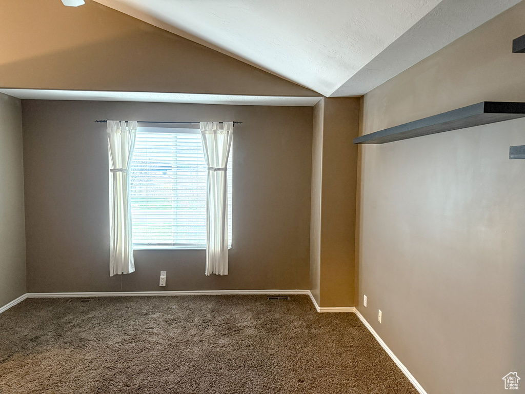 Carpeted spare room with baseboards and vaulted ceiling