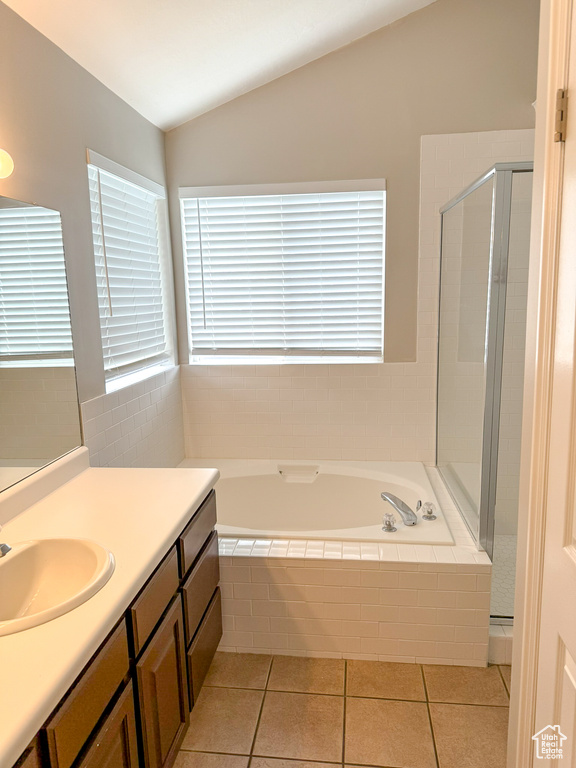 Bathroom with lofted ceiling, a garden tub, a stall shower, tile patterned flooring, and vanity