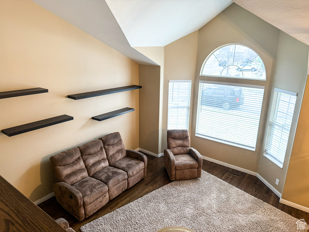 Living room with dark wood-style floors, baseboards, and lofted ceiling