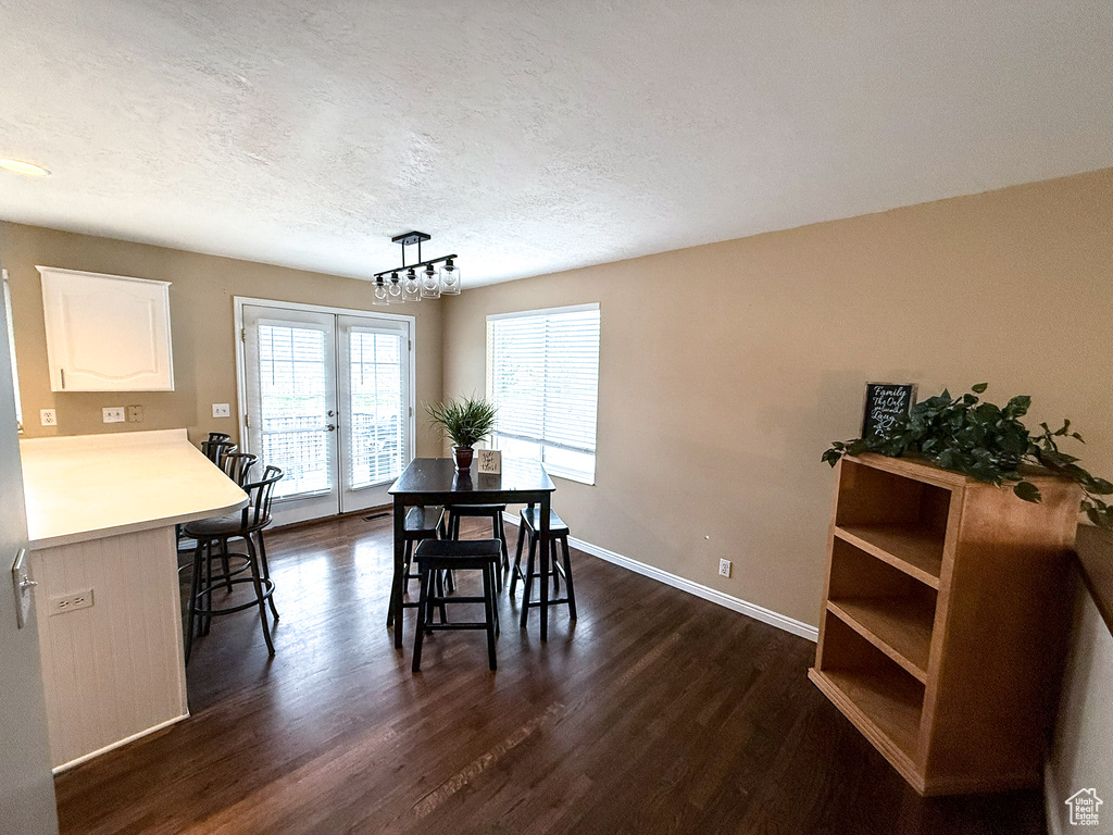 Dining room featuring french doors, a textured ceiling, dark wood-type flooring, and baseboards