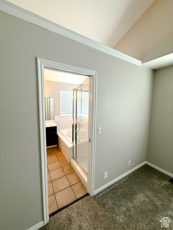 Unfurnished room featuring light colored carpet, baseboards, ornamental molding, and light tile patterned floors