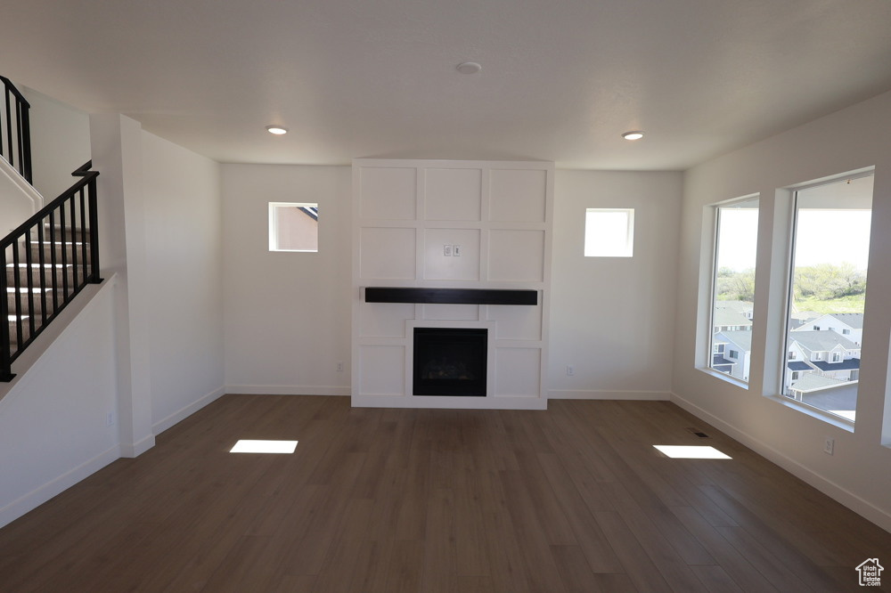 Unfurnished living room with baseboards, recessed lighting, wood finished floors, stairs, and a fireplace