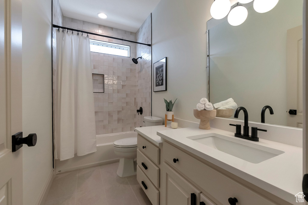 Bathroom featuring tile patterned flooring, toilet, vanity, and shower / tub combo with curtain