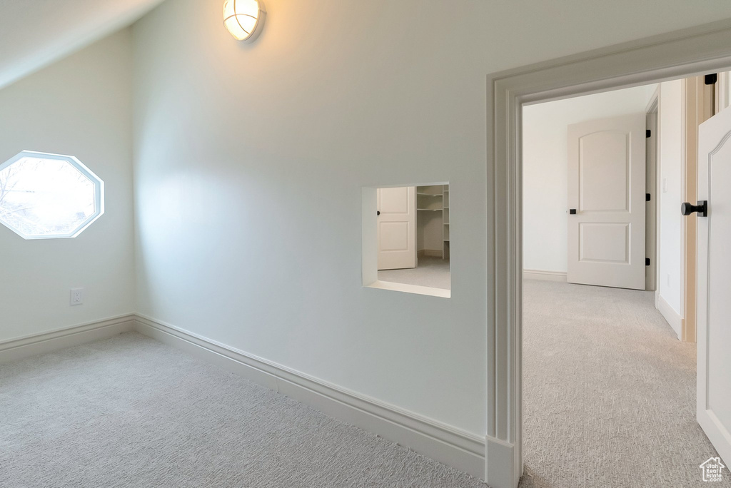 Interior space with baseboards, light carpet, and vaulted ceiling