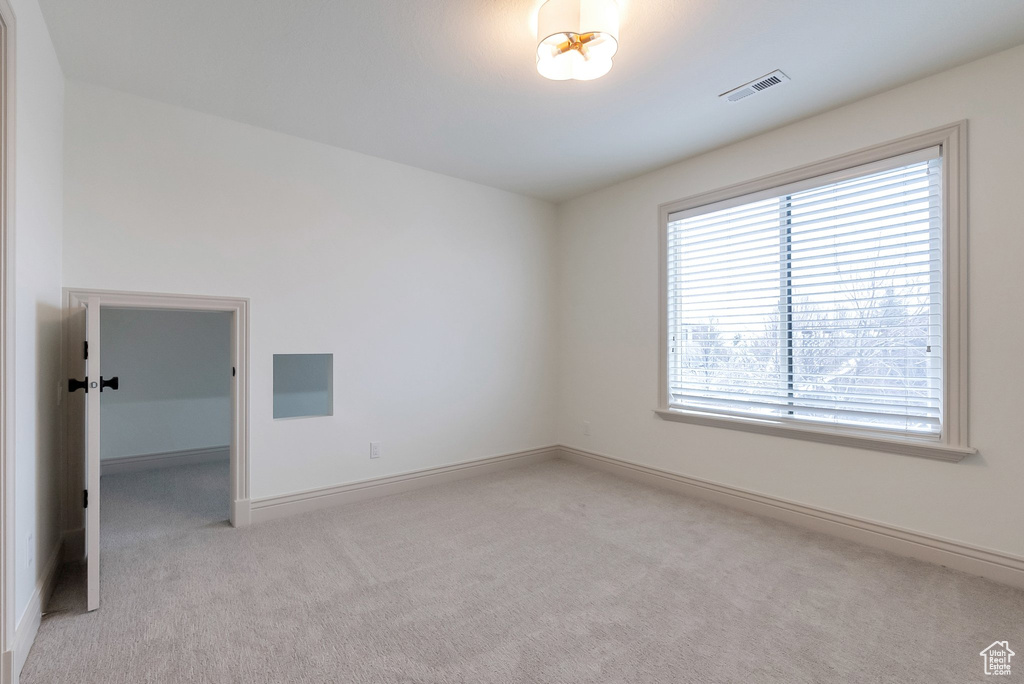 Empty room featuring baseboards, visible vents, and light carpet