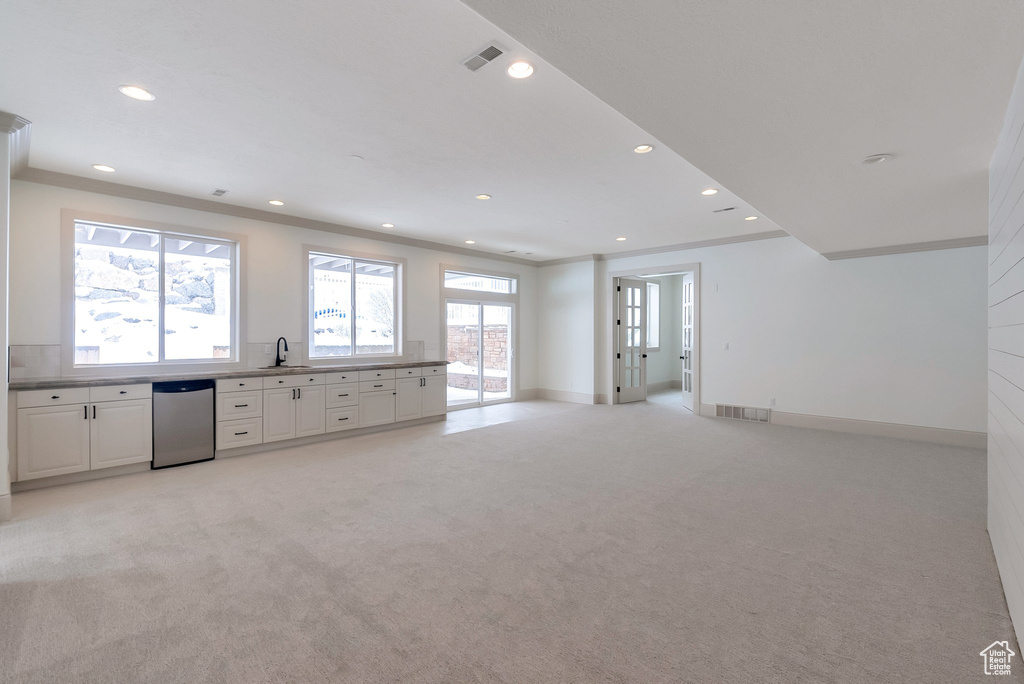 Interior space with crown molding, light colored carpet, baseboards, and a sink