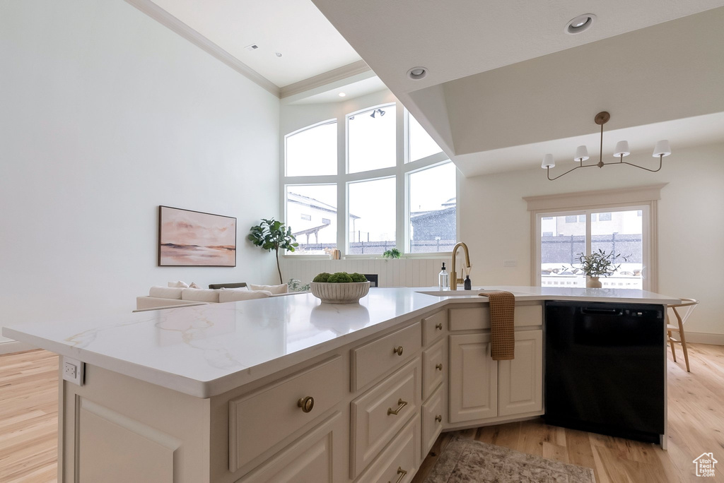 Kitchen featuring a sink, light stone counters, black dishwasher, a high ceiling, and light wood finished floors