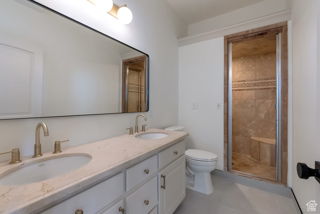 Bathroom with a sink, toilet, a stall shower, and double vanity