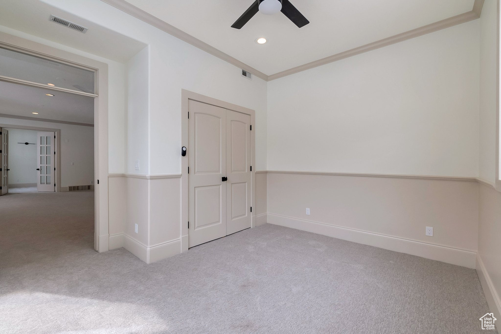 Unfurnished room with visible vents, carpet, a ceiling fan, and crown molding