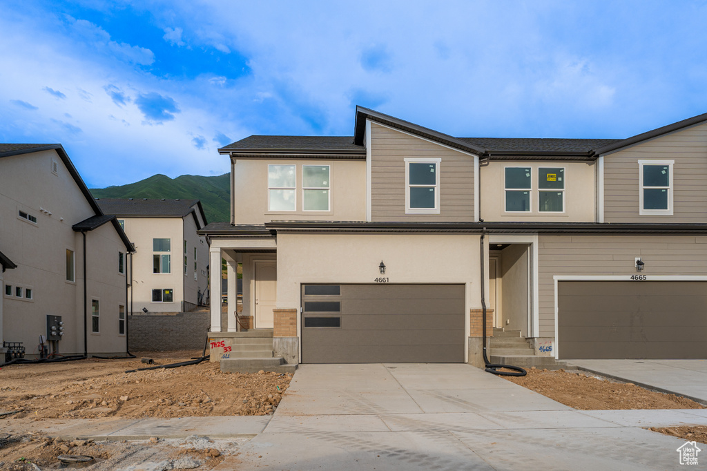 View of front of home featuring a garage, concrete driveway, a mountain view, and stucco siding