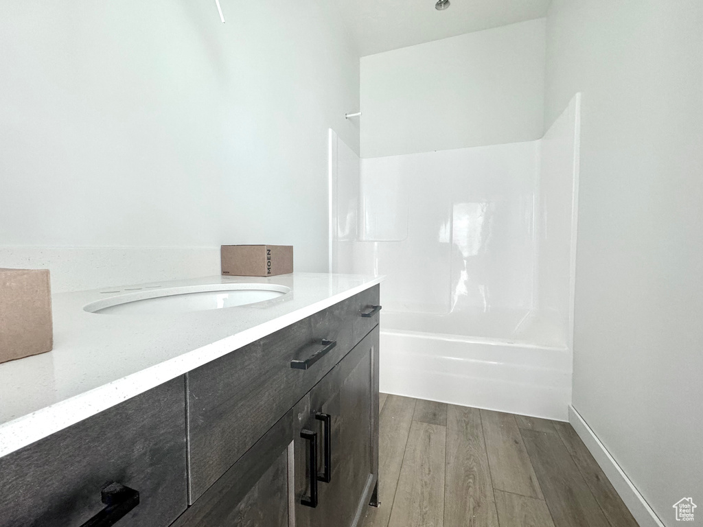 Full bath featuring vanity, shower / bathing tub combination, wood finished floors, and baseboards