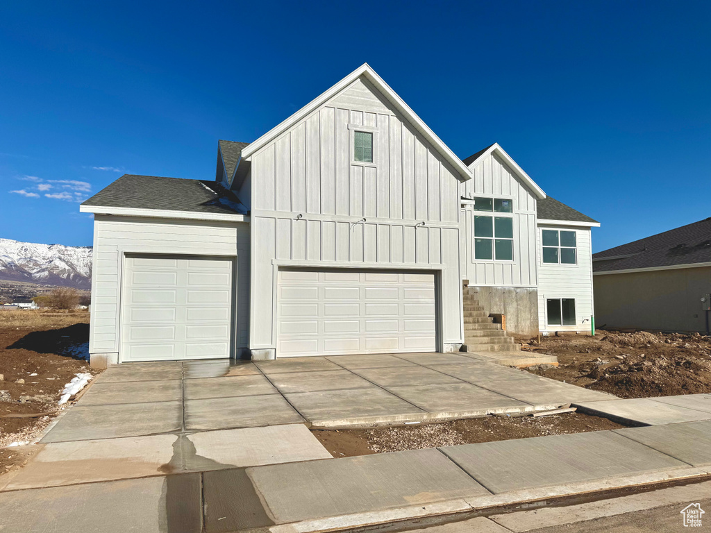 Modern inspired farmhouse with a garage, board and batten siding, concrete driveway, and a shingled roof
