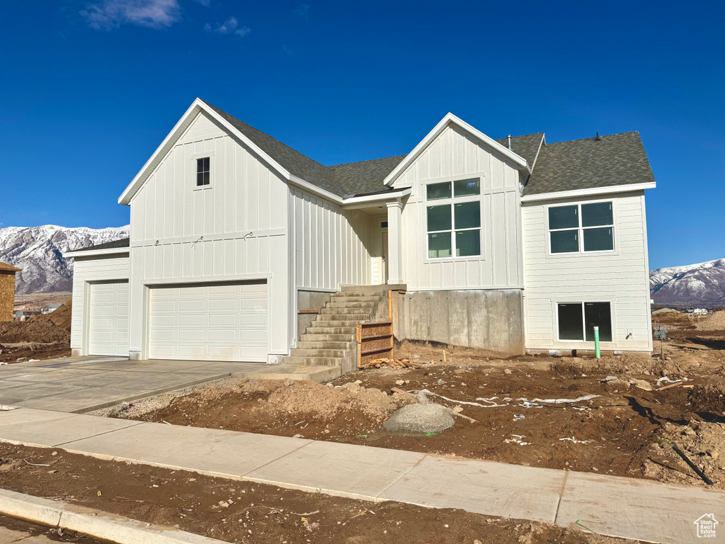 Modern farmhouse with a mountain view, board and batten siding, concrete driveway, and a shingled roof