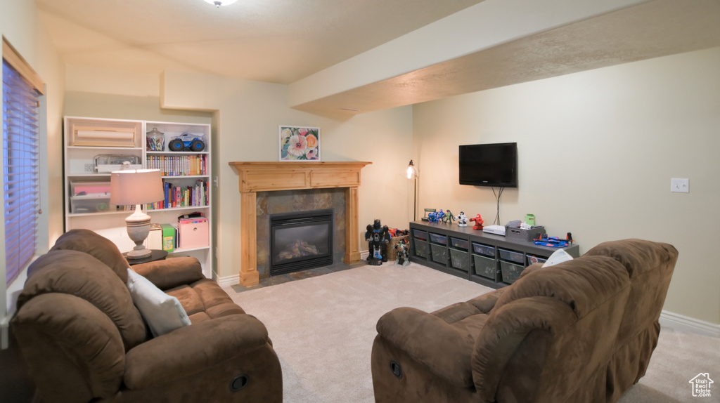 Living room featuring baseboards, carpet flooring, and a tiled fireplace