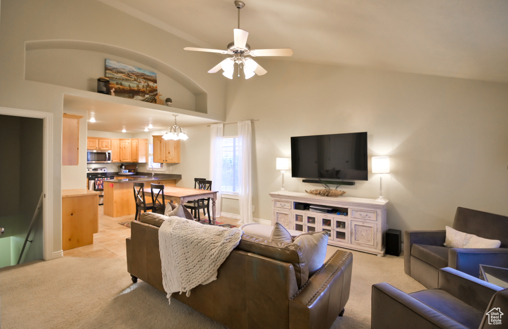 Living room with baseboards, light colored carpet, ceiling fan, and high vaulted ceiling