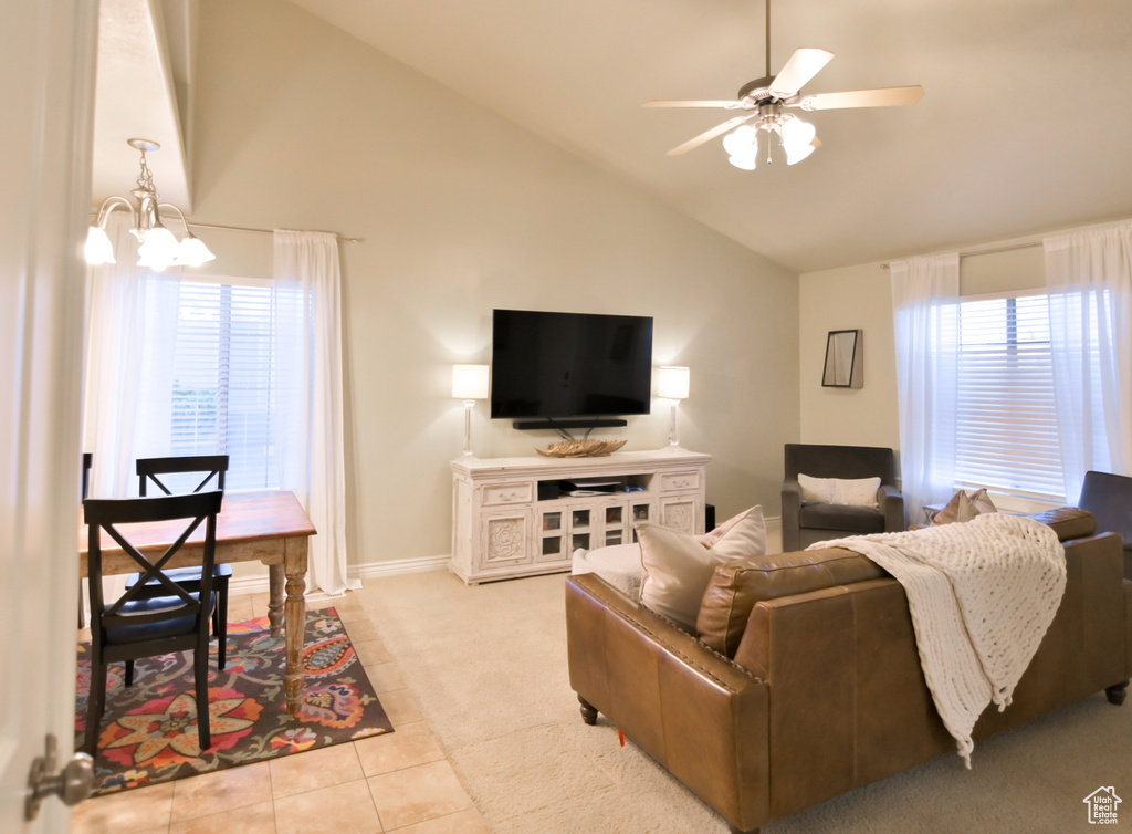 Tiled living area featuring carpet flooring, ceiling fan with notable chandelier, high vaulted ceiling, and baseboards
