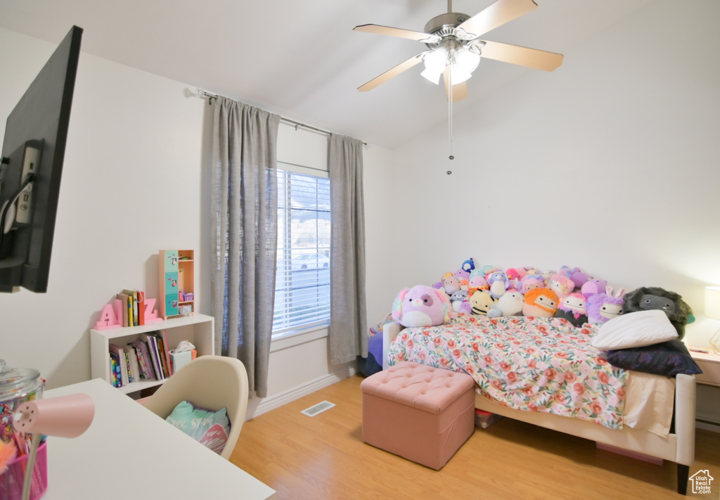 Bedroom with lofted ceiling, wood finished floors, visible vents, and ceiling fan