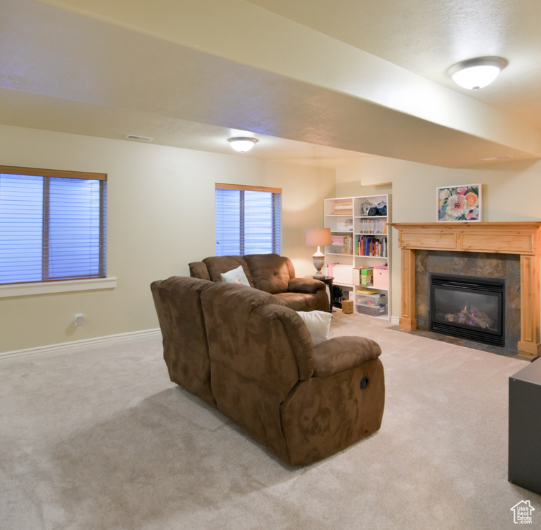 Carpeted living room featuring a fireplace with flush hearth, baseboards, and visible vents