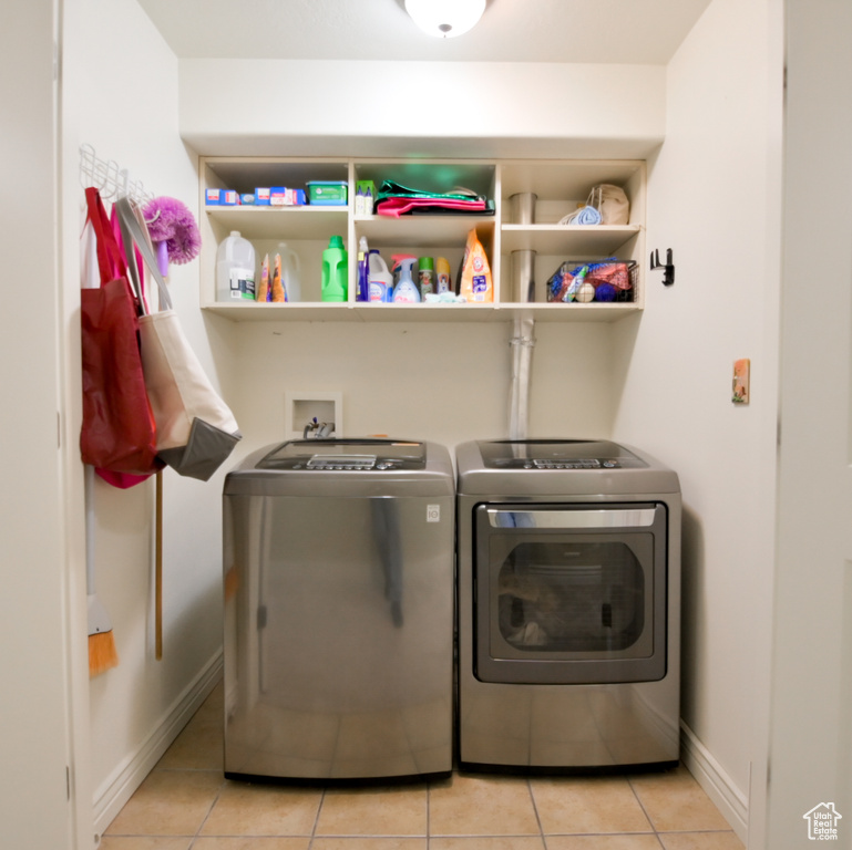 Laundry room featuring washer and dryer, laundry area, light tile patterned floors, and baseboards