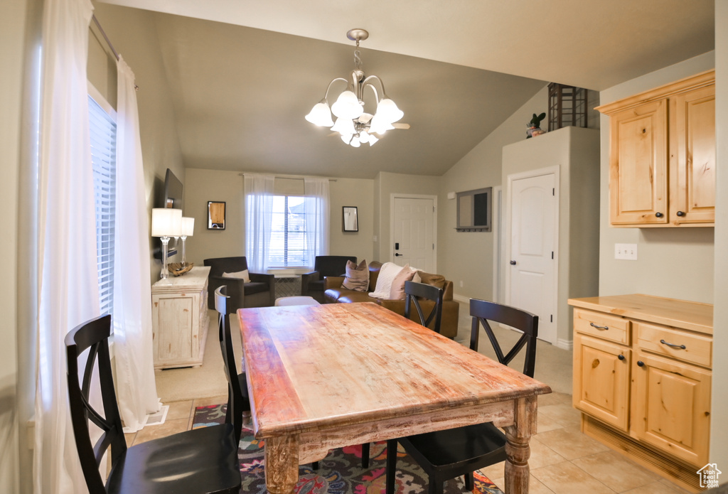 Dining space with light tile patterned floors, an inviting chandelier, and vaulted ceiling