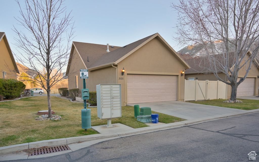 View of front facade with a front lawn, fence, stucco siding, driveway, and an attached garage