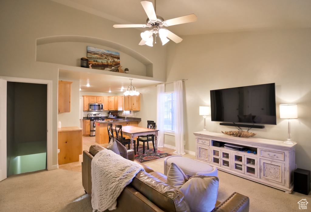 Living area with baseboards, light colored carpet, ceiling fan, and high vaulted ceiling